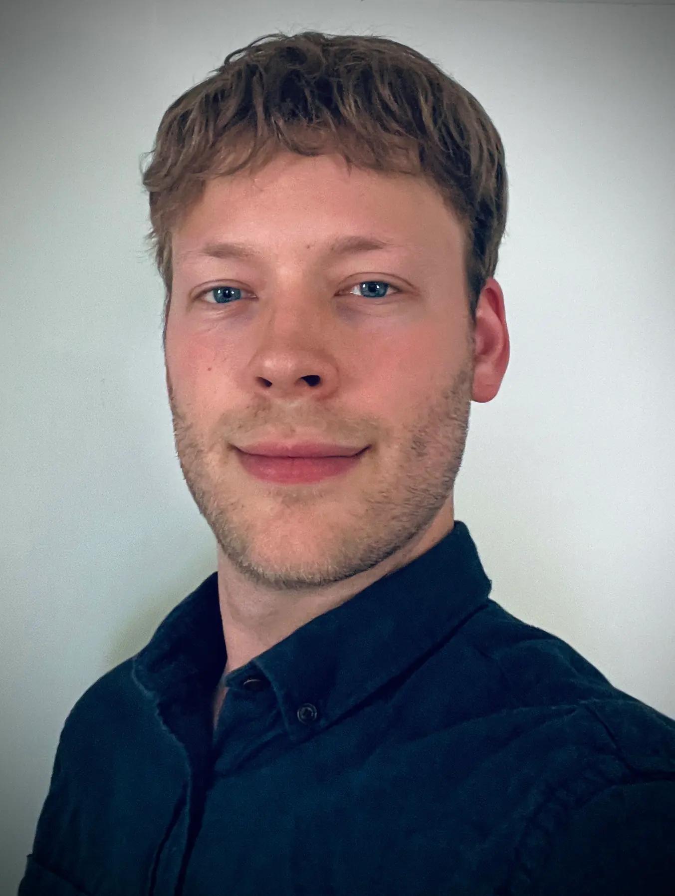 Portrait of a young man wearing a blue shirt against a neutral background