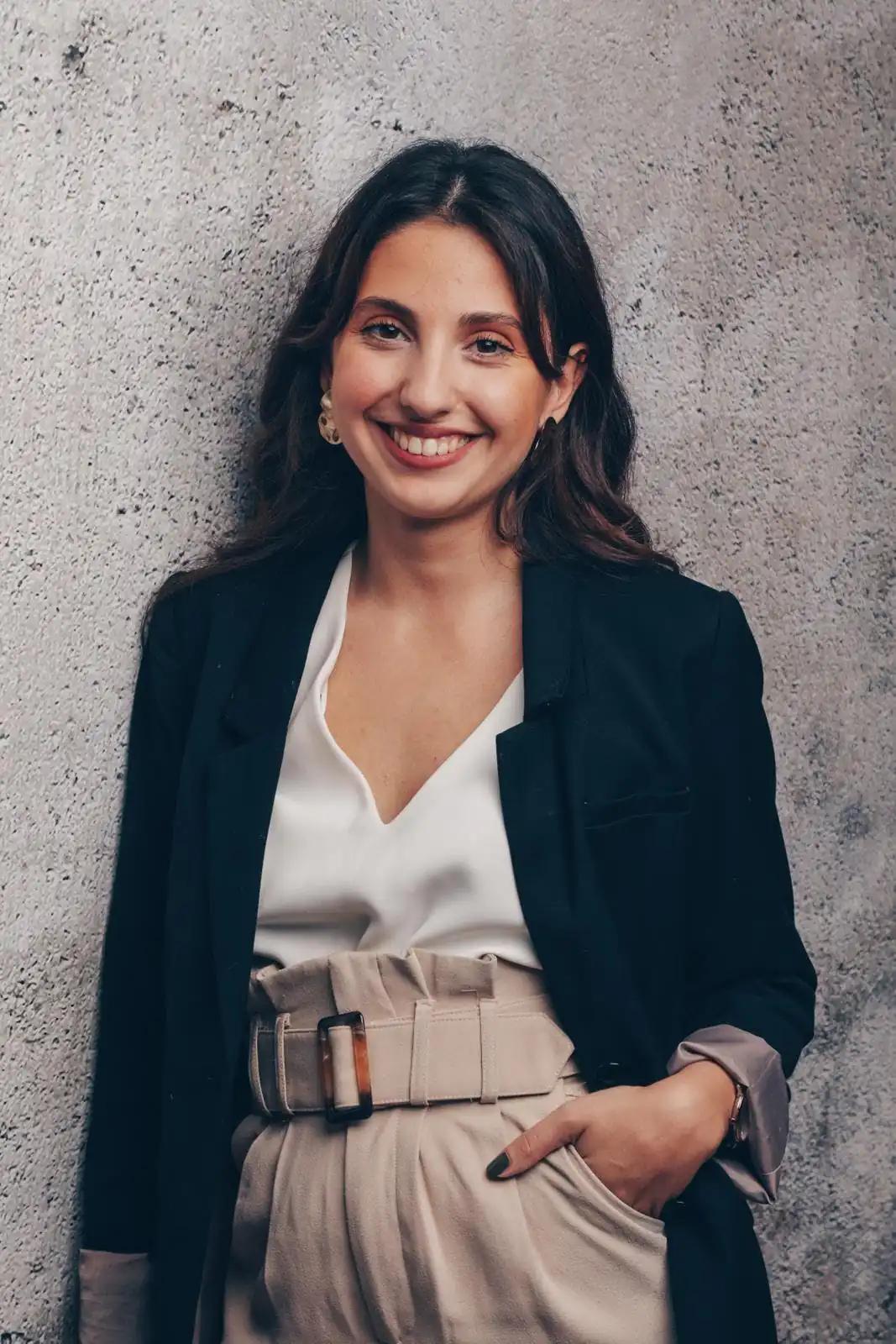 Portrait of a smiling woman against a wall.