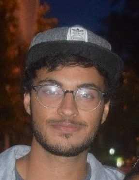 Portrait of a man wearing glasses and a hat at night.